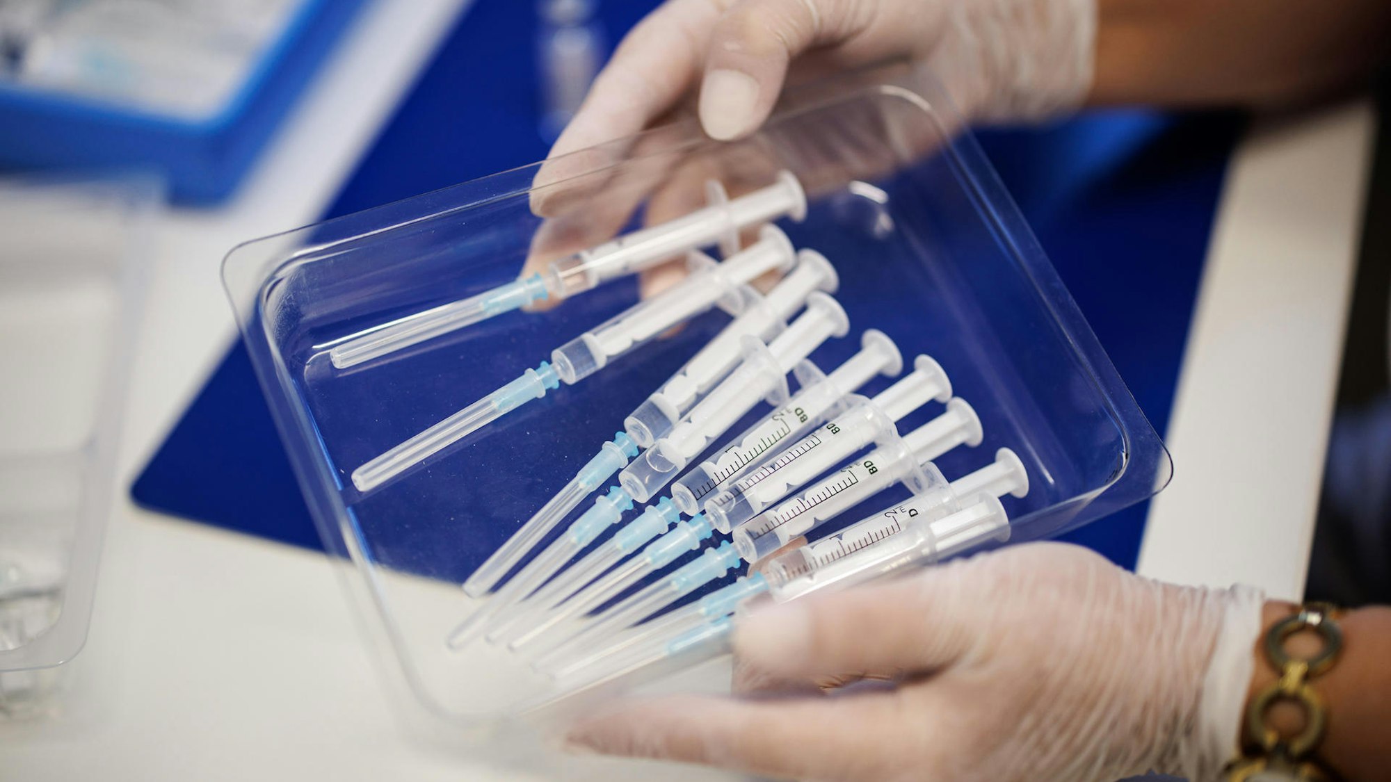 Spritzen mit einer Corona-Impfung liegen auf einem blauen Tablett.