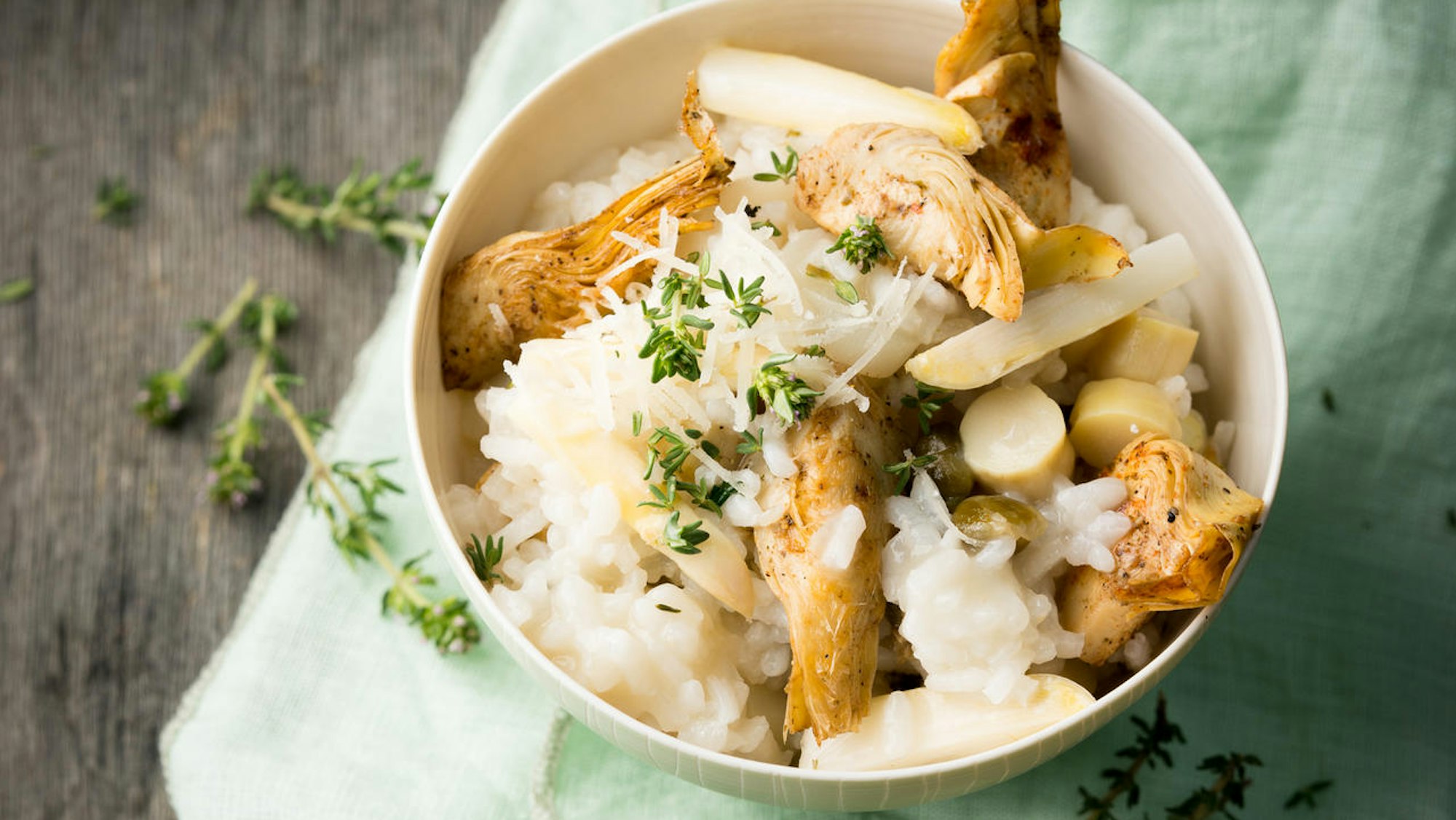 Spargelrisotto mit Artischocken und Kapern, serviert in einer Schale, edel angerichtet