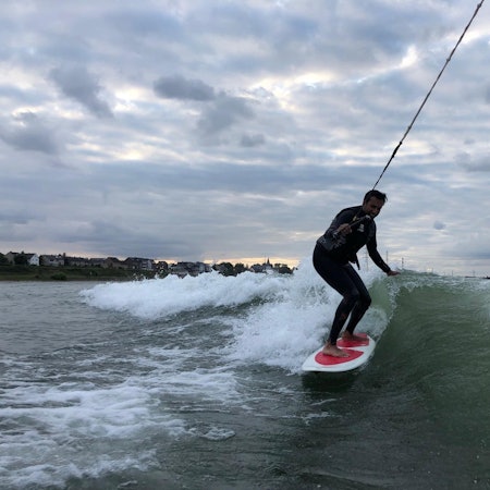 Ein junger Mann surft auf dem Rhein.