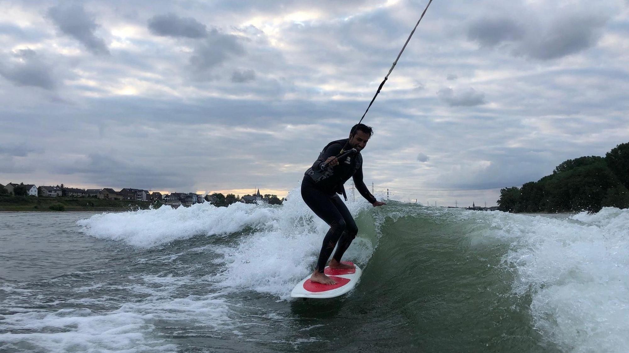 Ein junger Mann surft auf dem Rhein.