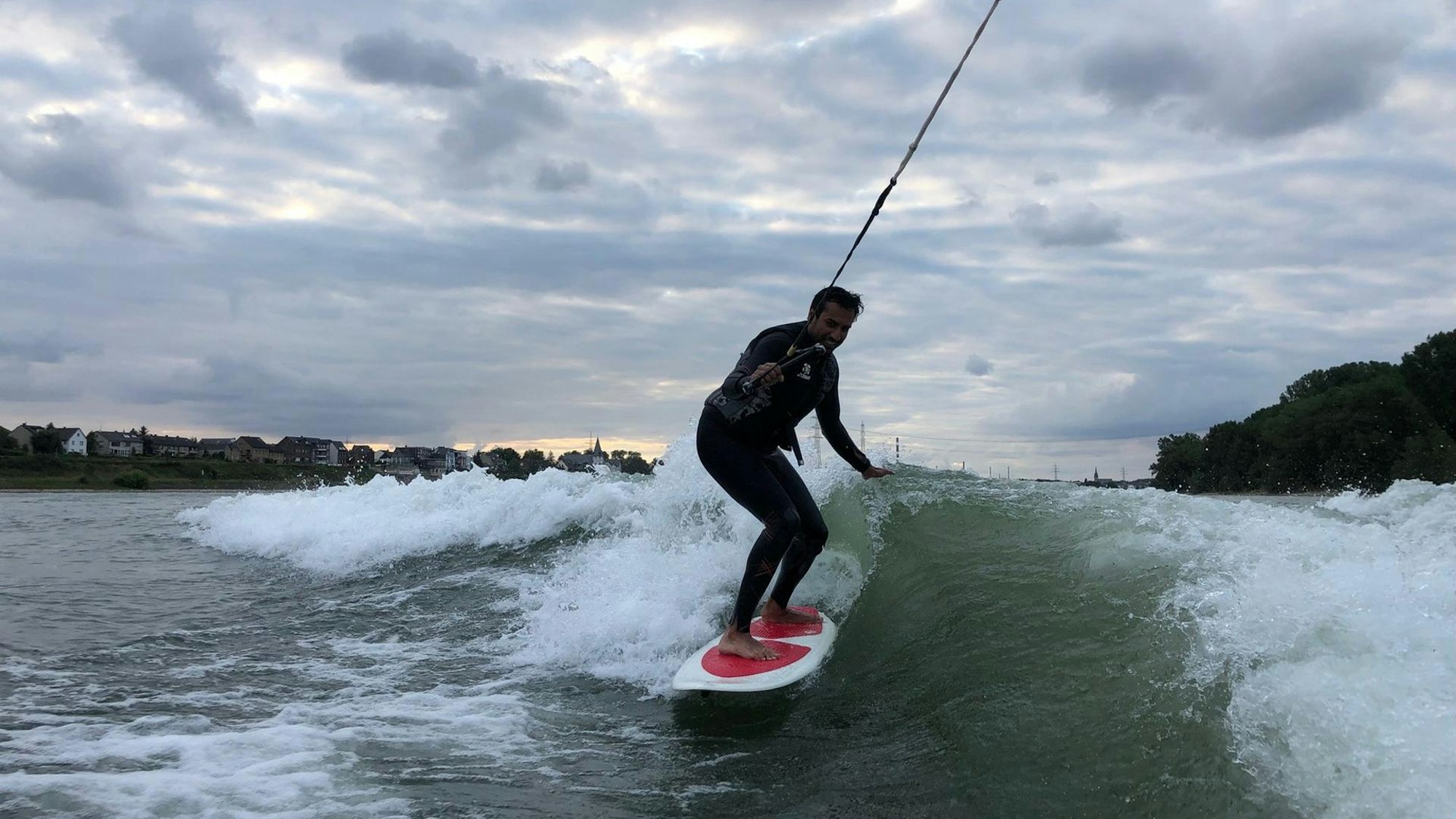 Ein junger Mann surft auf dem Rhein.