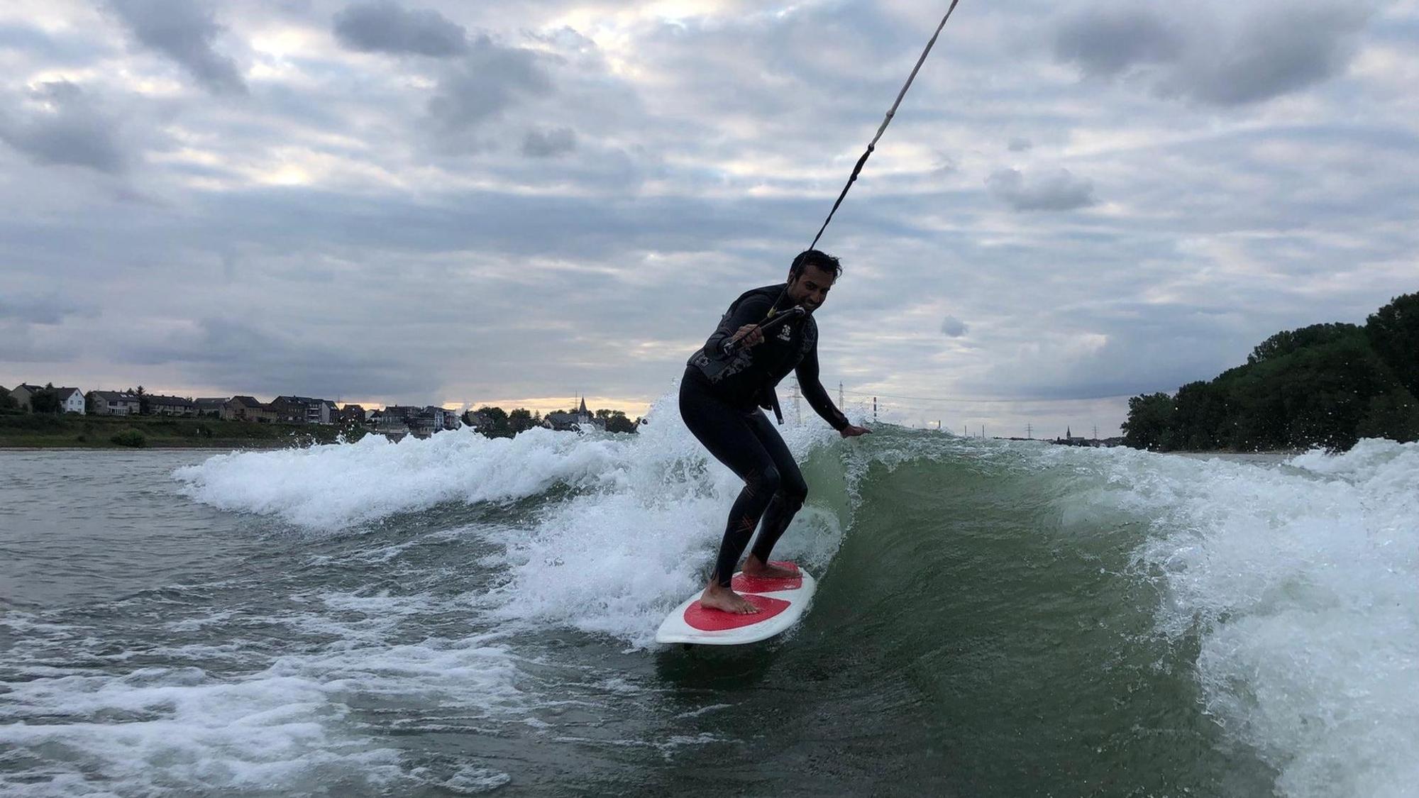 Ein junger Mann surft auf dem Rhein.