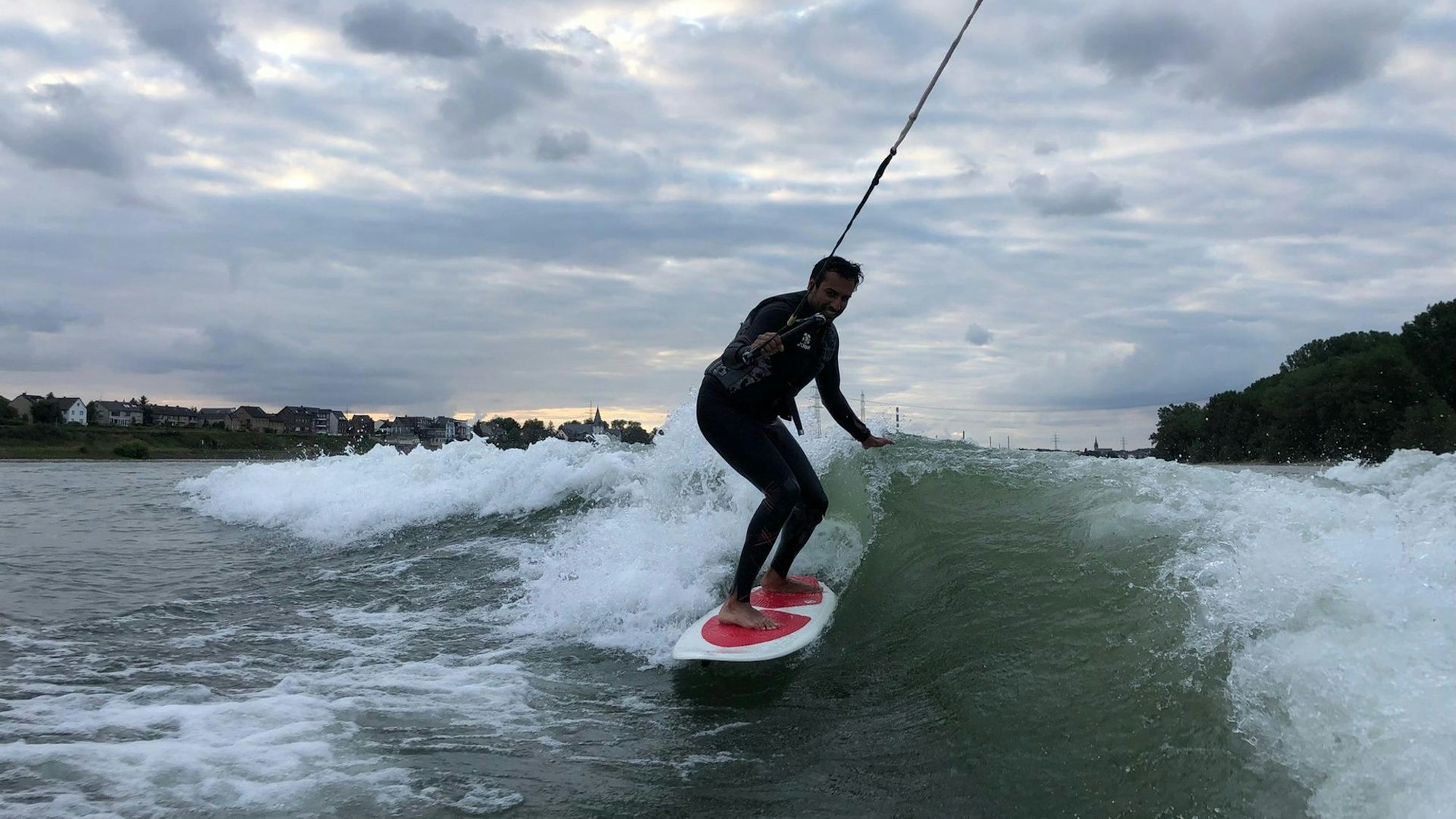 Ein junger Mann surft auf dem Rhein.