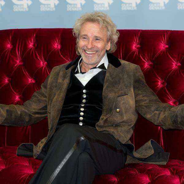Thomas Gottschalk sitzt auf einer Couch und lacht.