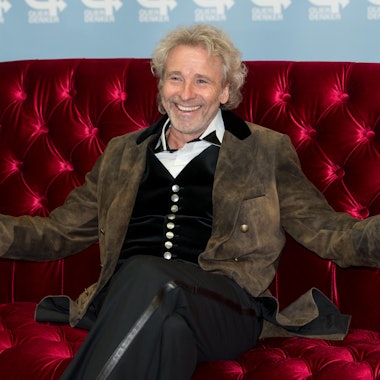 Thomas Gottschalk sitzt auf einer Couch und lacht.