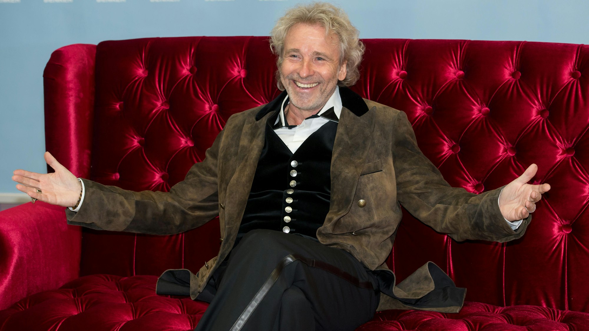 Thomas Gottschalk sitzt auf einer Couch und lacht.