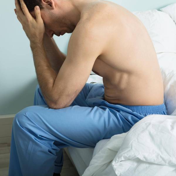 Mann sitzt auf dem Bett und zweifelt