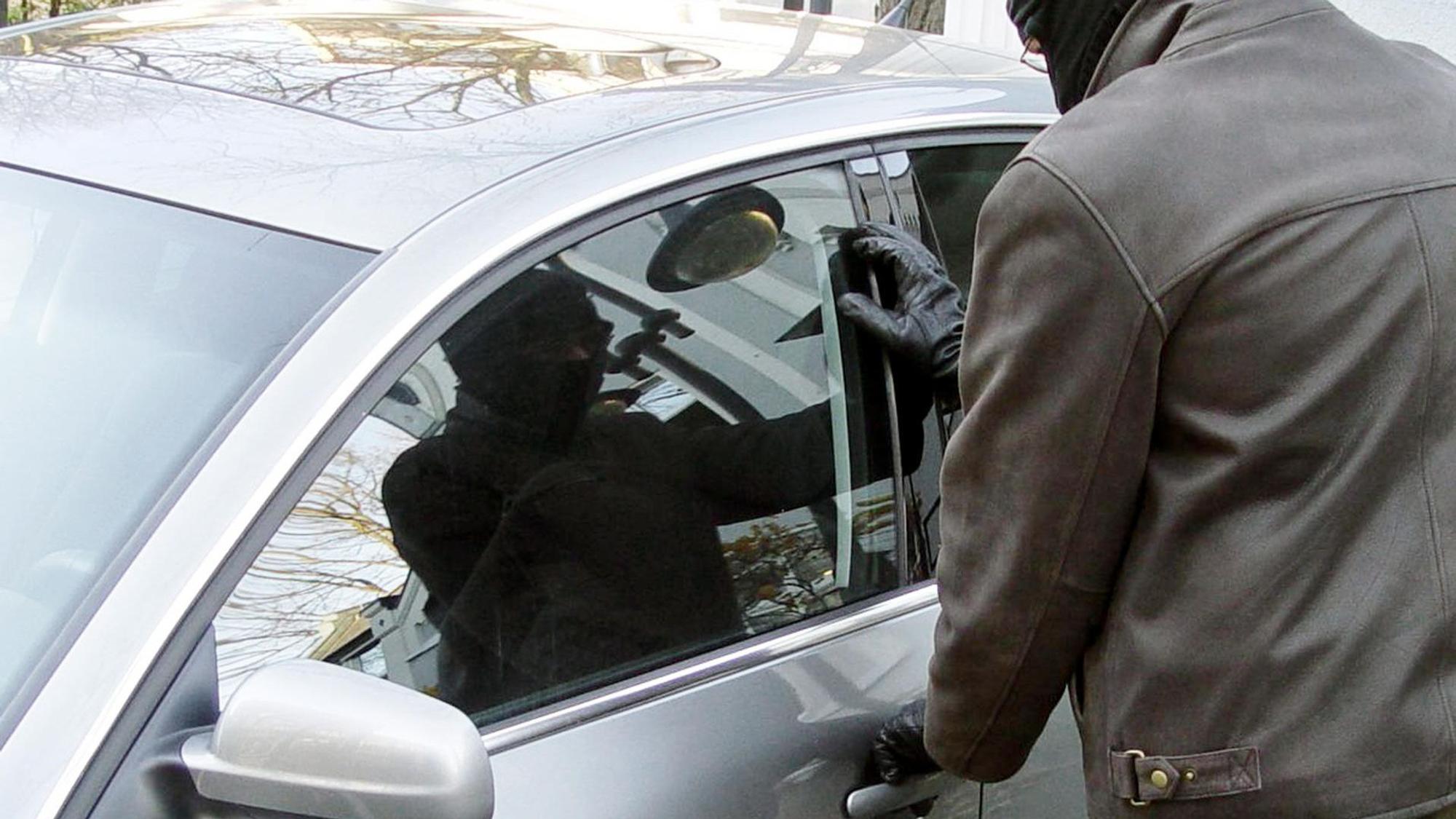 Ein Mann steht vor einem Auto und versucht, die Tür zu öffnen