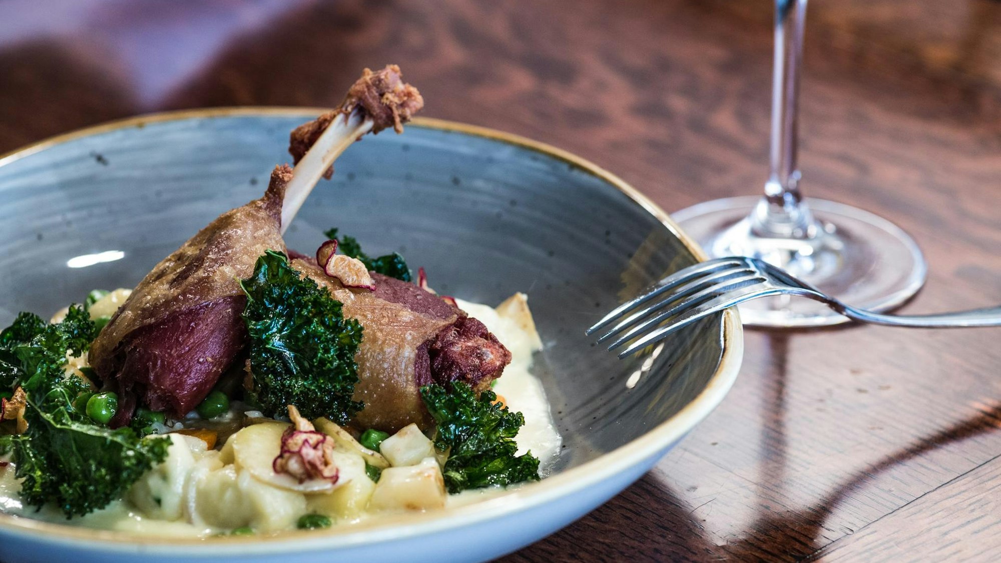 Geflügel mit Kartoffelbrei. Im Hintergrund ein Weinglas.