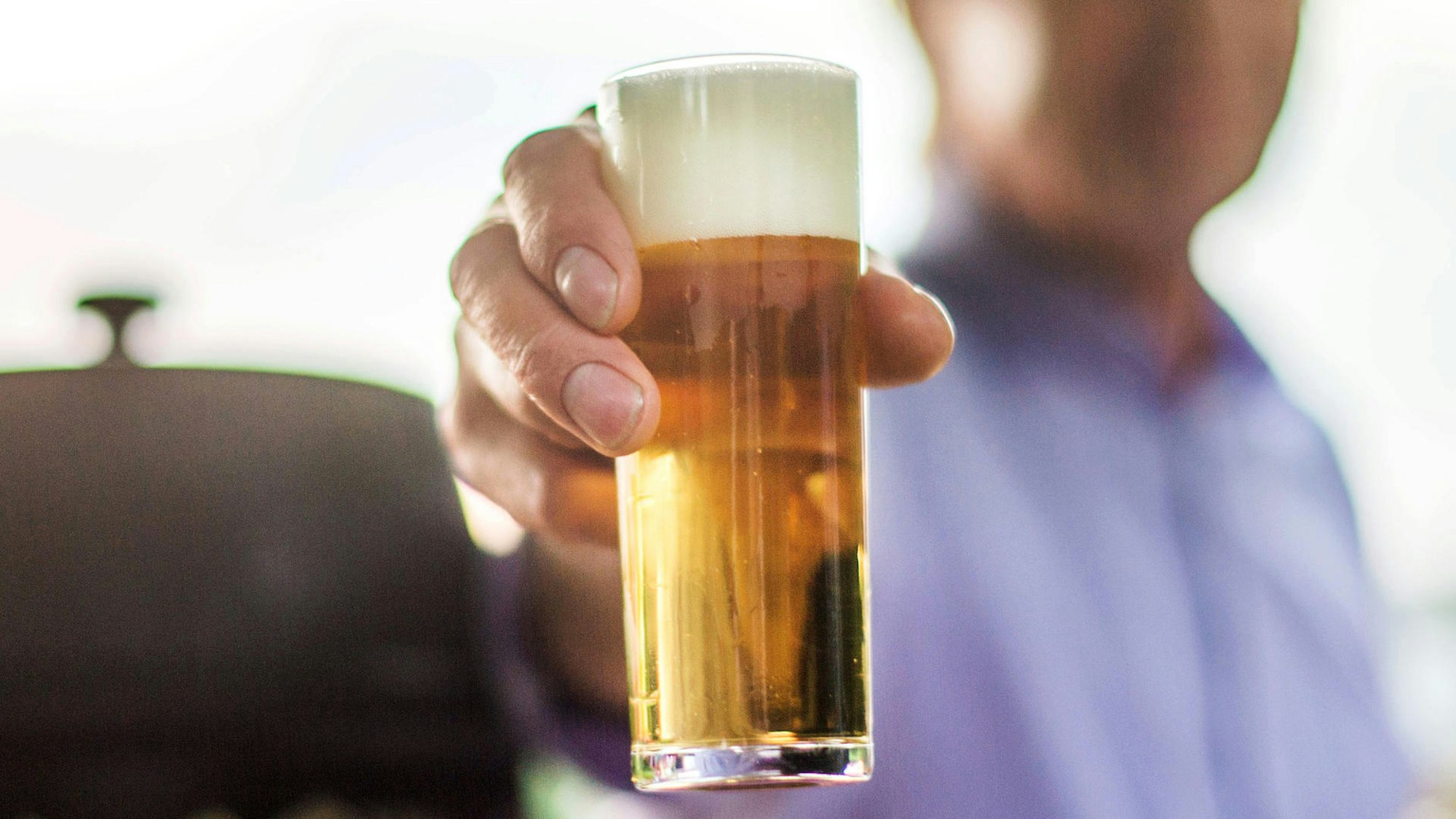 Eine Hand hält ein Glas Kölsch.