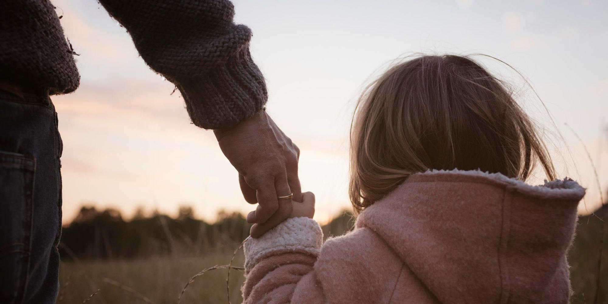 Ein Vater hält seine Tochter an der Hand
