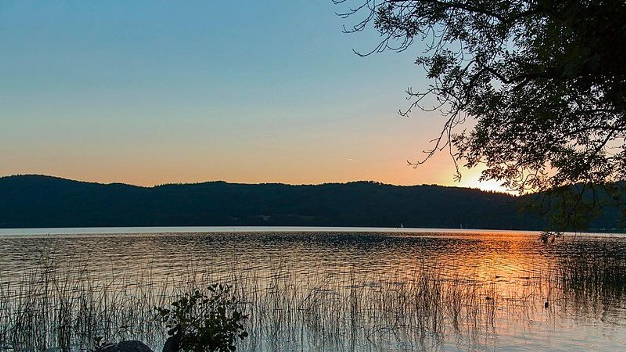 Hinter dem Laacher See geht die Sonne unter.
