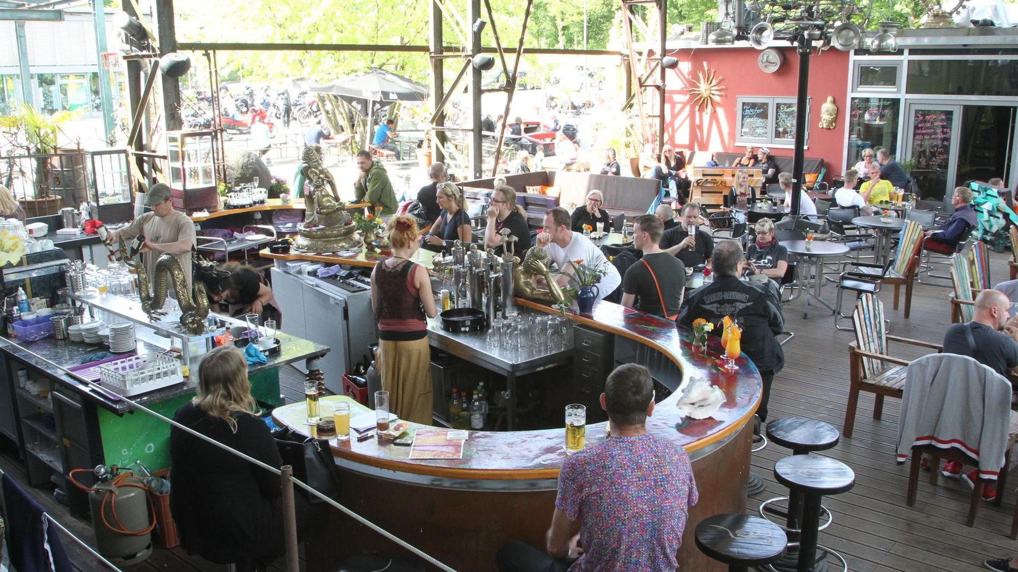 Blick auf den Außenbereich eines Restaurants mit einer großen Theke, Tischen und Stühlen.