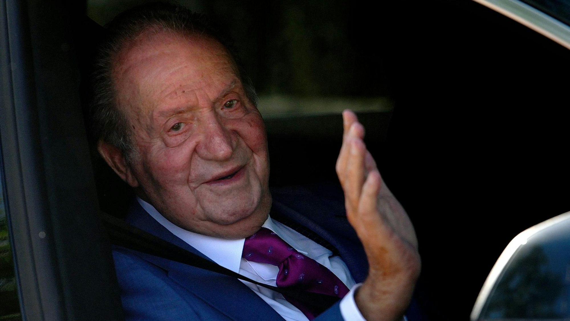 Juan Carlos winkt in einem Auto.