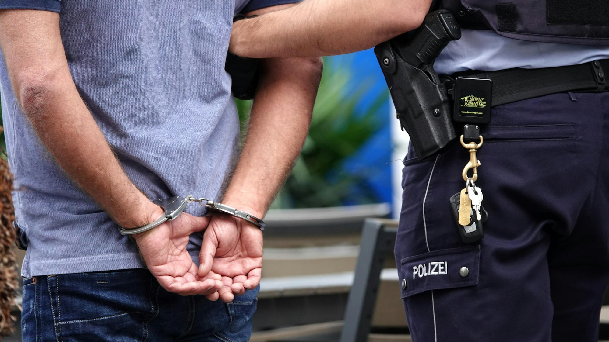 Ein Mann wird in Handschellen abgeführt.
