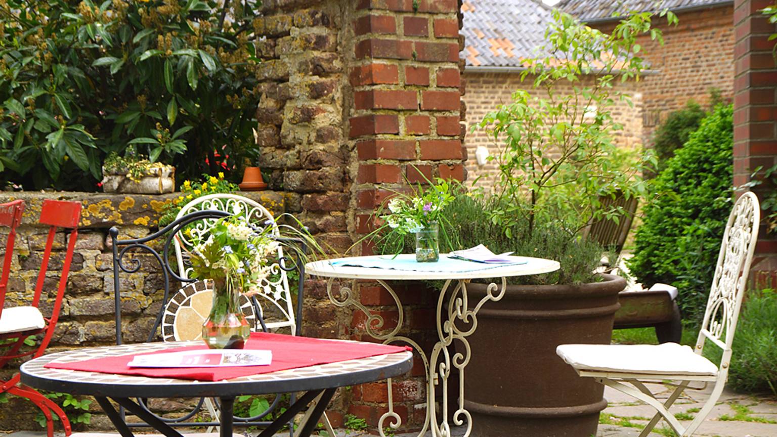 Gartentische und Stühle aus Metall stehen in einem Innenhof