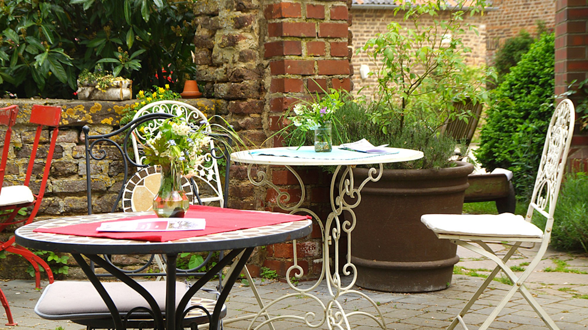Gartentische und Stühle aus Metall stehen in einem Innenhof
