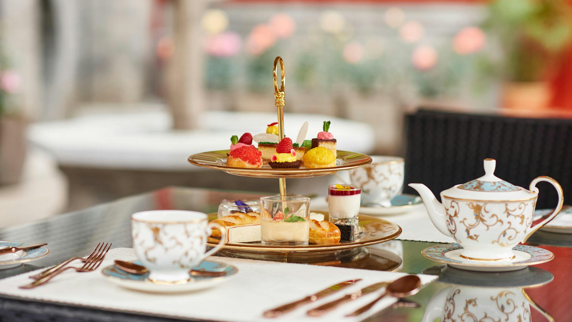 Eine Tea Time ist auf einem Tisch angerichtet, mit edlen Törtchen und feinem Geschirr.