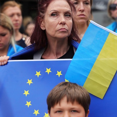 Eone Frau hält eine EU-Flagge und eine ukrainische Flagge in der Hand.