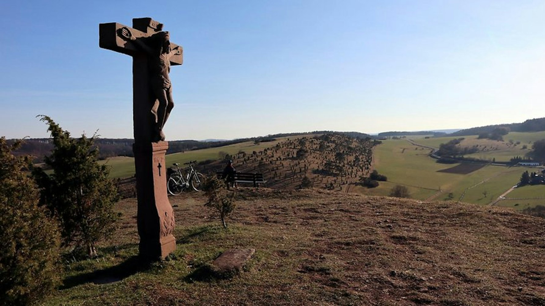 Gipfelkreuz aus Stein, blauer Himmel, weite Sicht