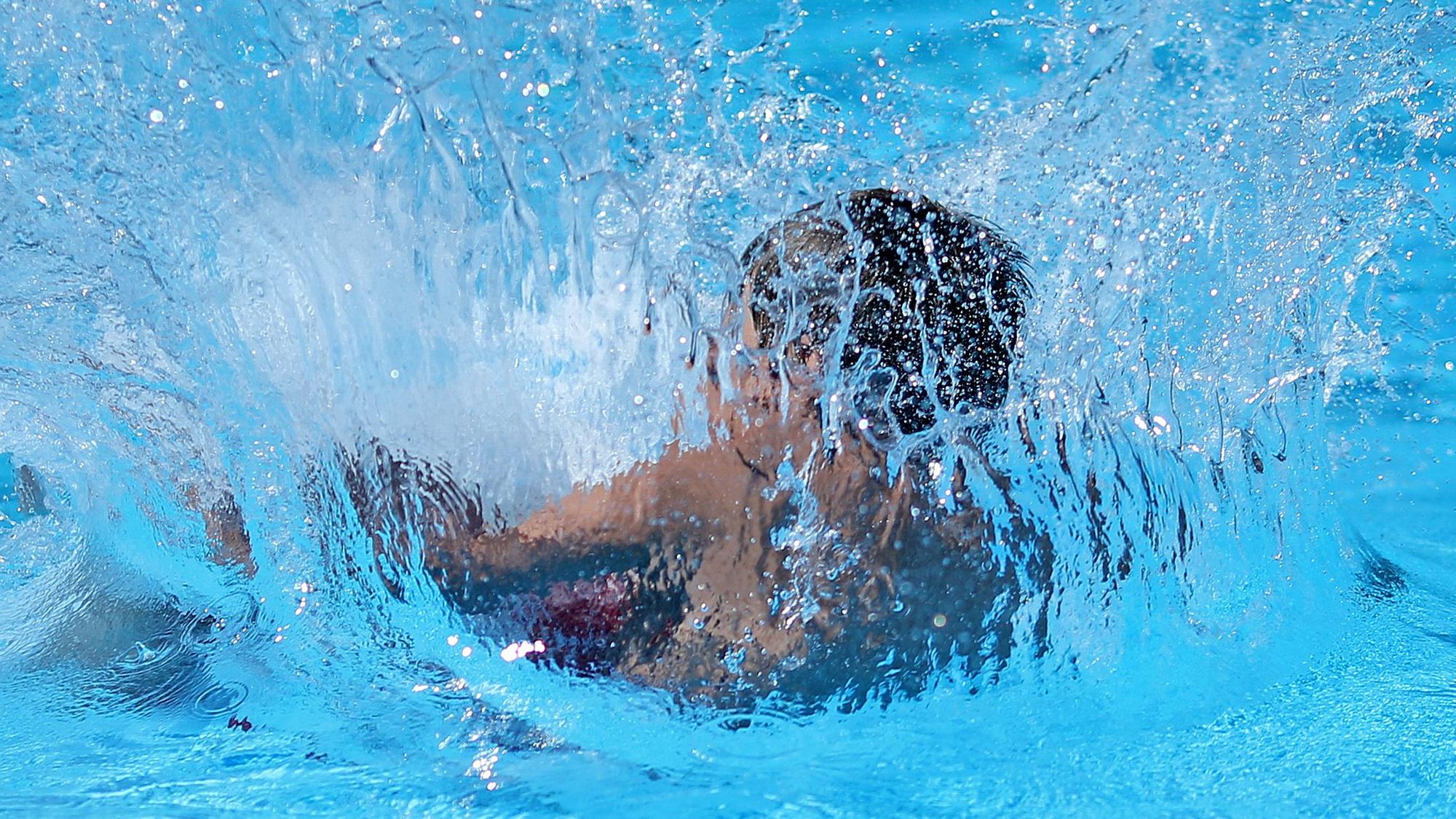 Ein Kind springt in ein Schwimmbecken.
