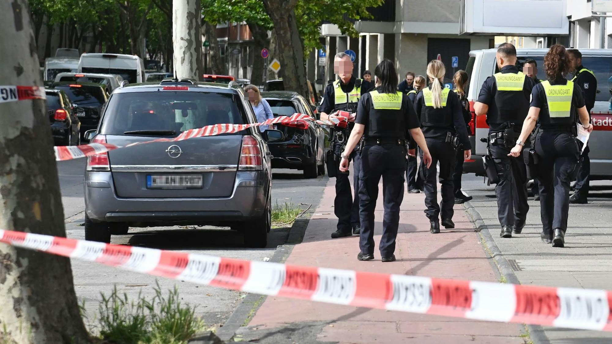 Einsatzkräfte des Ordnungsamtes sperren eine Straße mit einem Flatterband ab.
