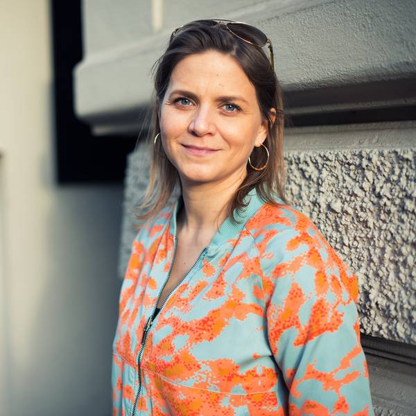 Sandra Schneeloch, Stadträtin der Grünen, steht vor einer Hauswand. Sie trägt eine ins Haar gesteckte Sonnenbrille.