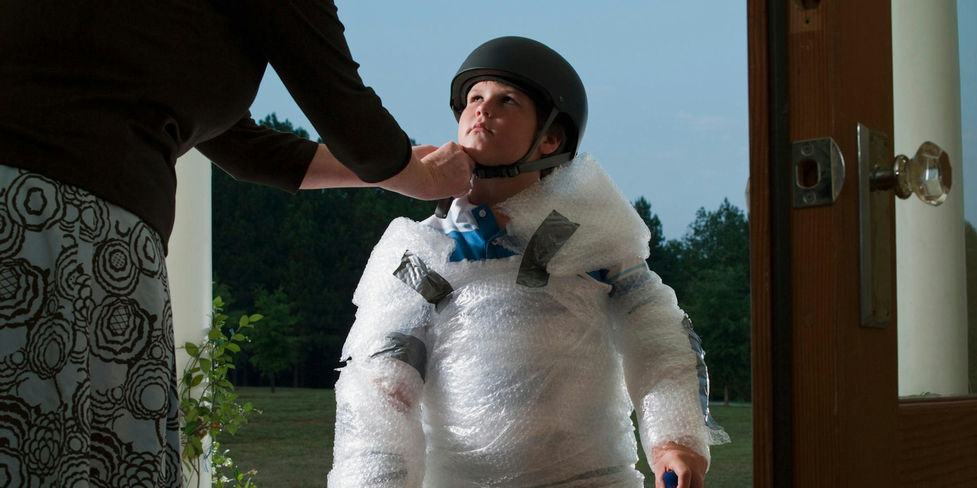 Ein Kind ist komplett mit Schutzfolie umwickelt und trägt einen Helm.