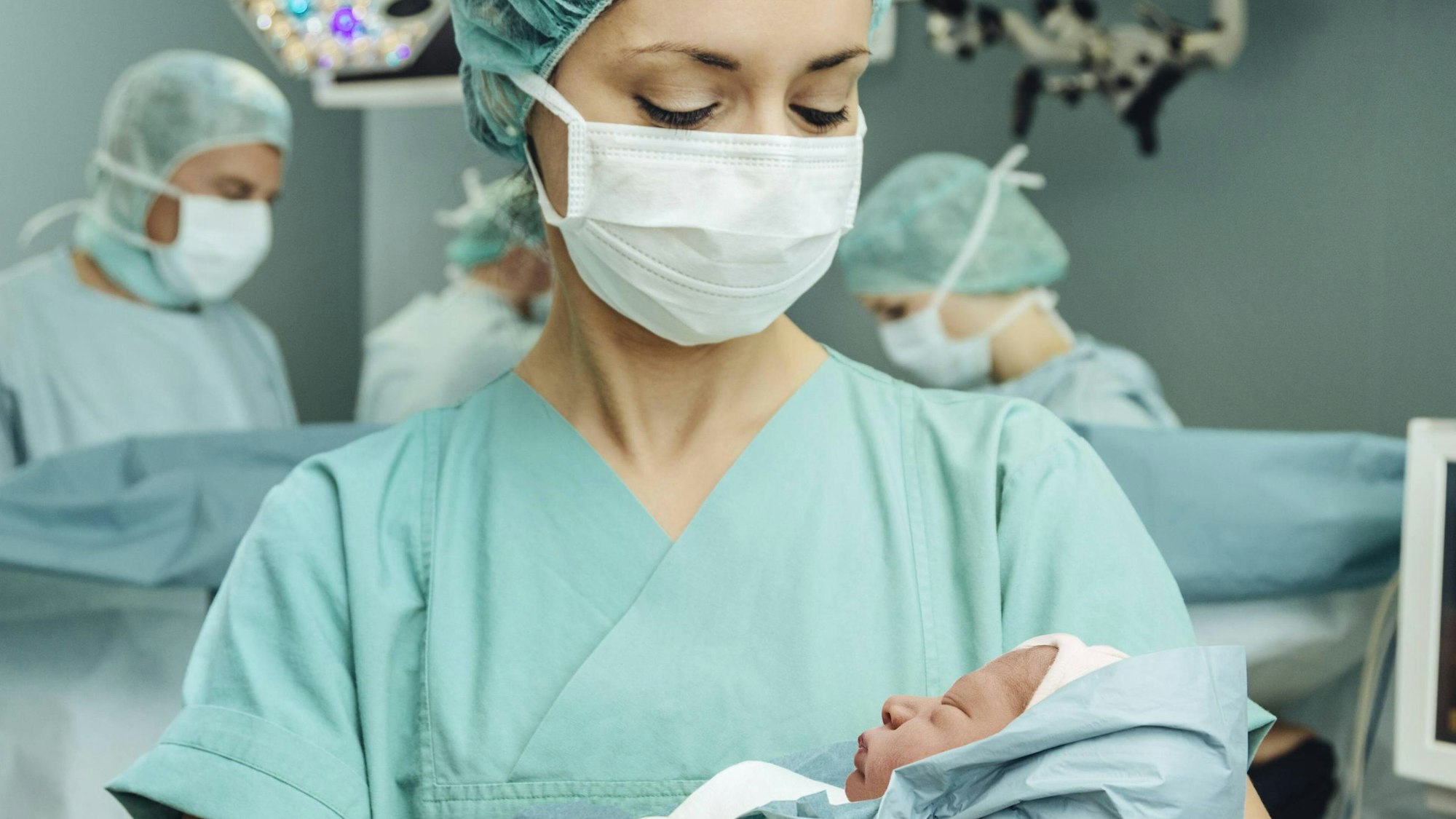 Hebamme mit Baby im Arm