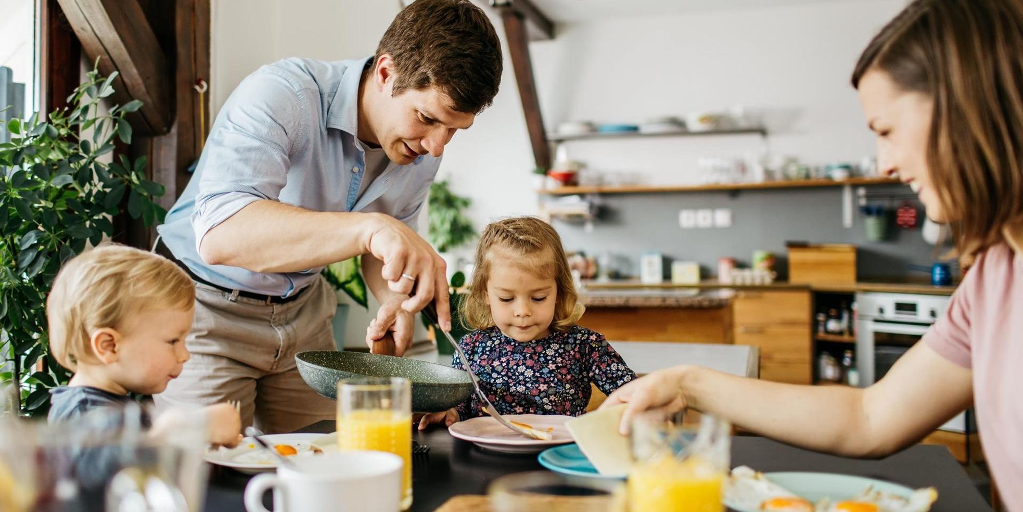 Eine Familie mit Vater, Mutter und zwei Kindern sitzt am Frühstückstisch