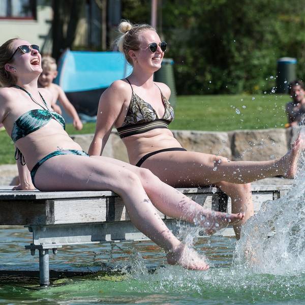 Frauen sitzen am Beckenrand eines Freibadbeckens