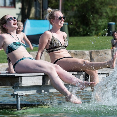 Frauen sitzen am Beckenrand eines Freibadbeckens
