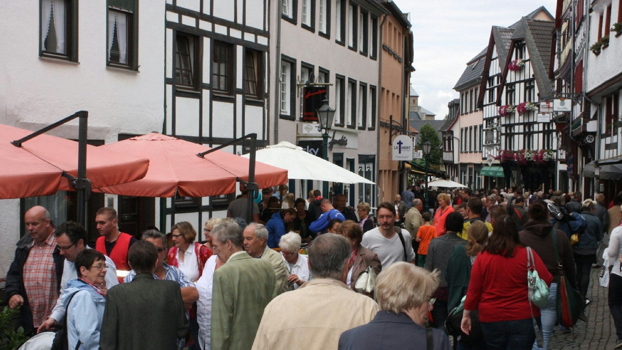 Menschen auf einer schmalen Gasse zwischen Fachwerkhäusern