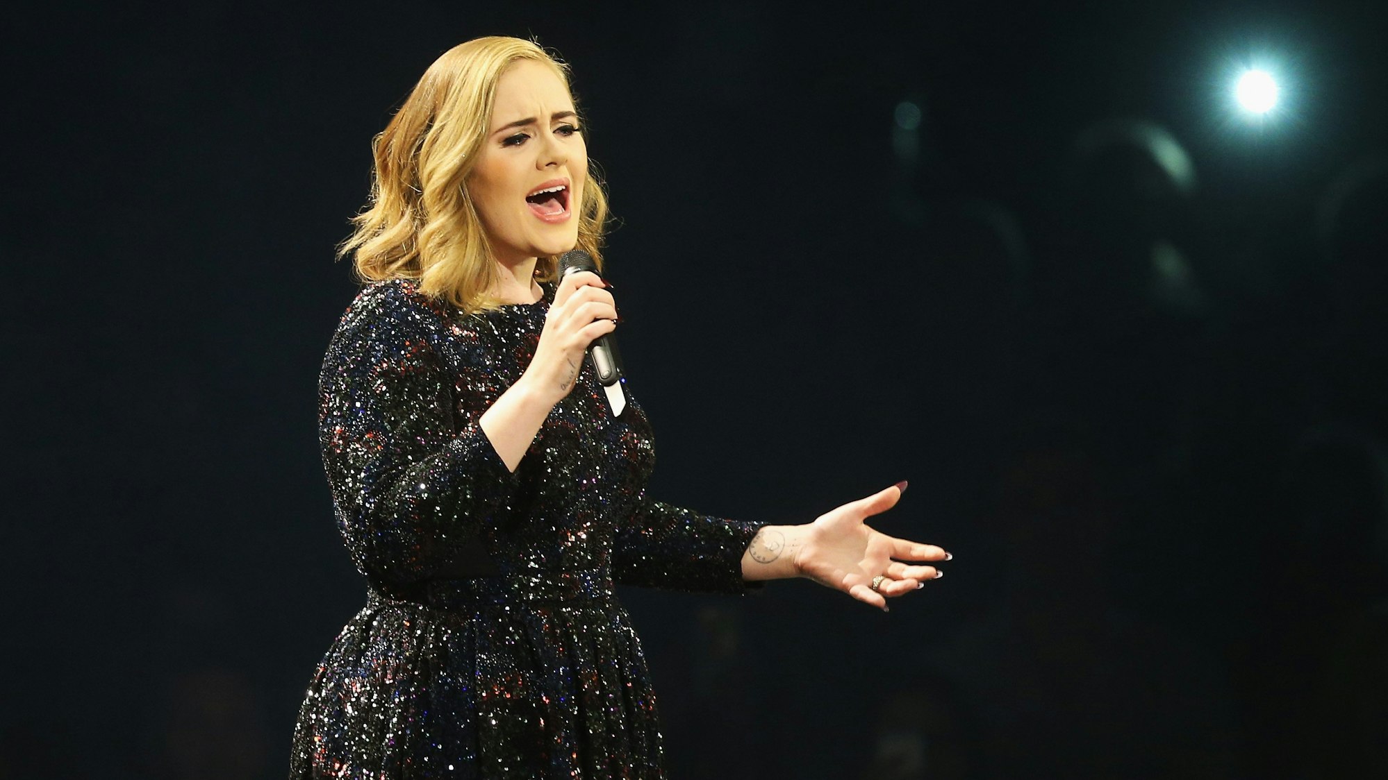 Adele singt in ein Mikrofon.