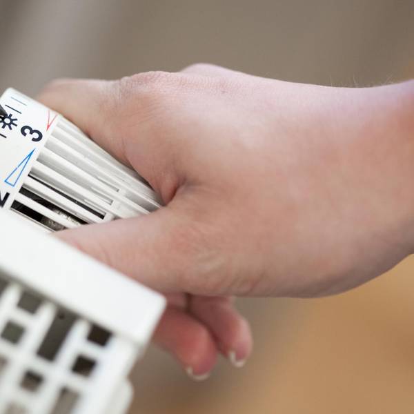 Hand dreht am Thermostat