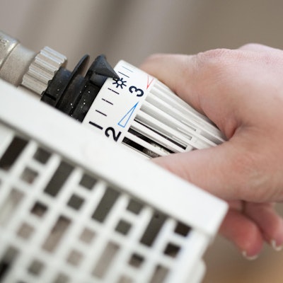 Hand dreht am Thermostat