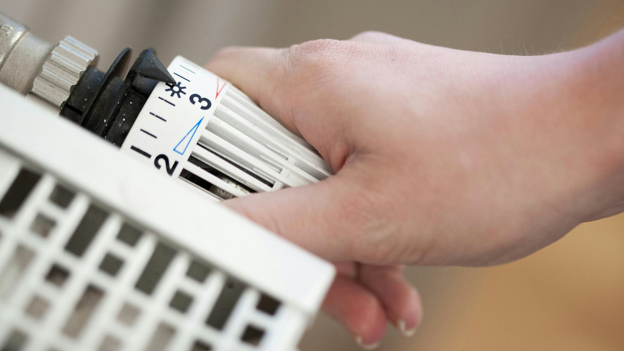 Das Foto zeigt eine Hand, die am Thermostat dreht.