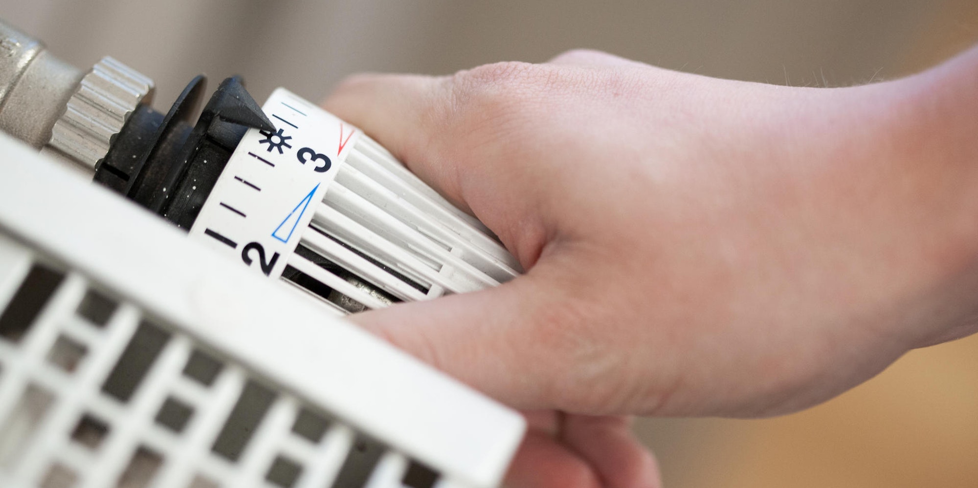 Hand dreht am Thermostat