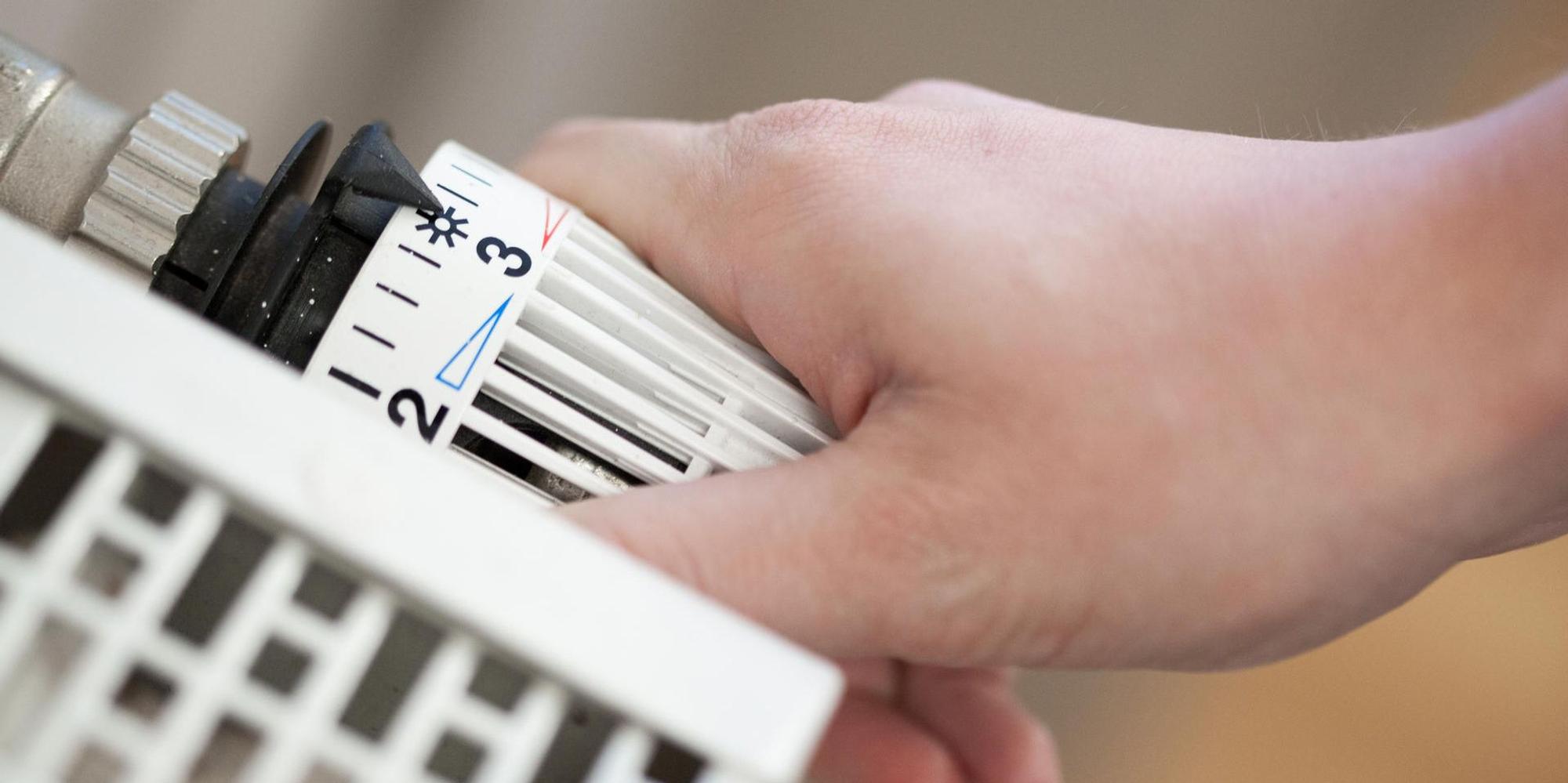 Hand dreht am Thermostat