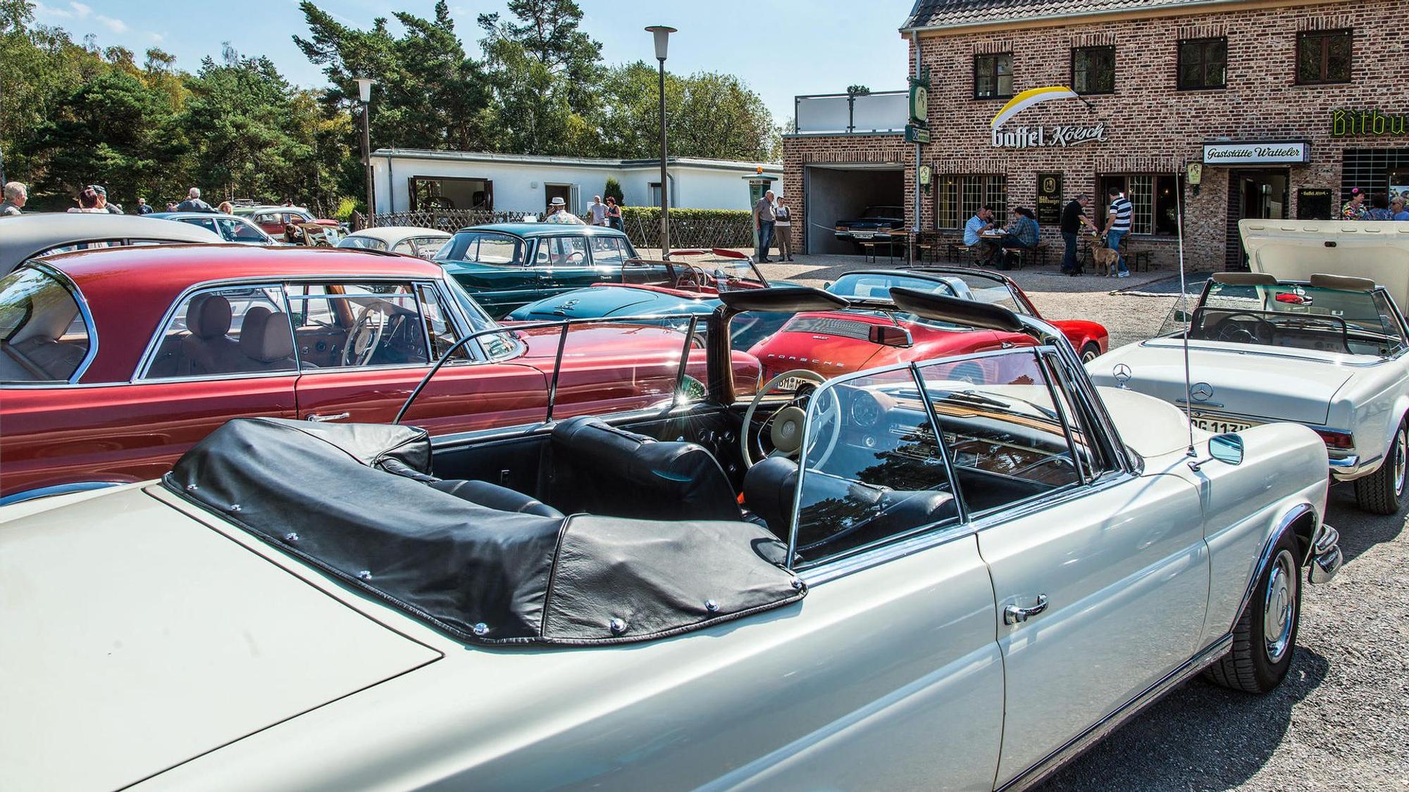 Oldtimer stehen auf einem Platz vor einer Gaststätte.