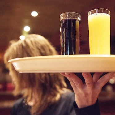 Eine Kellnerin trägt im Restaurant ein Tablett mit Getränken.