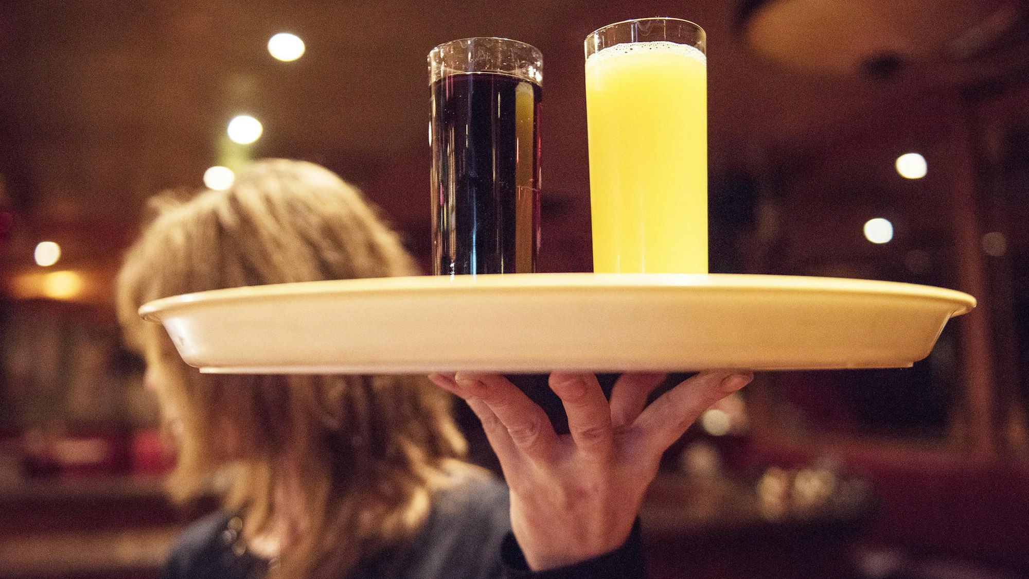 Eine Kellnerin trägt im Restaurant ein Tablett mit Getränken.