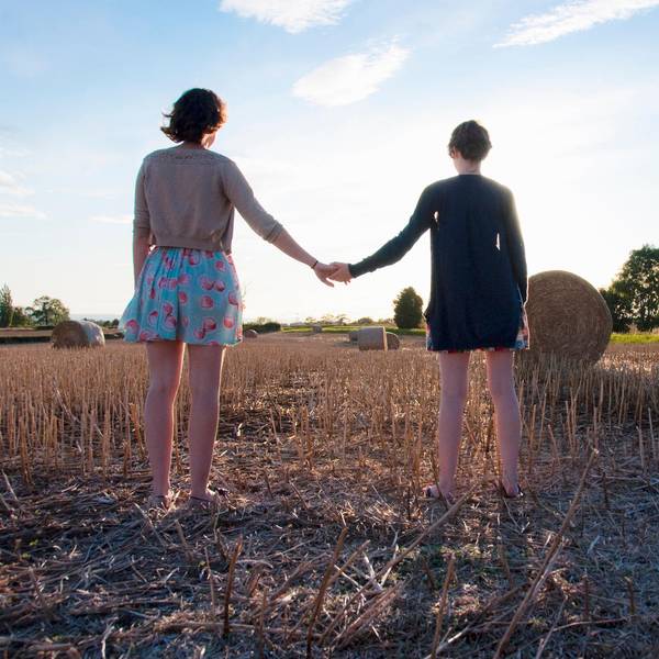 Zwei Frauen stehen auf einem Feld und halten sich an der Hand.