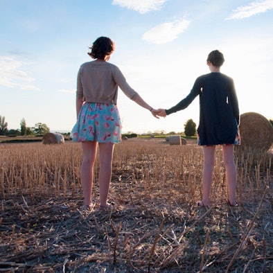 Zwei Frauen stehen auf einem Feld und halten sich an der Hand.