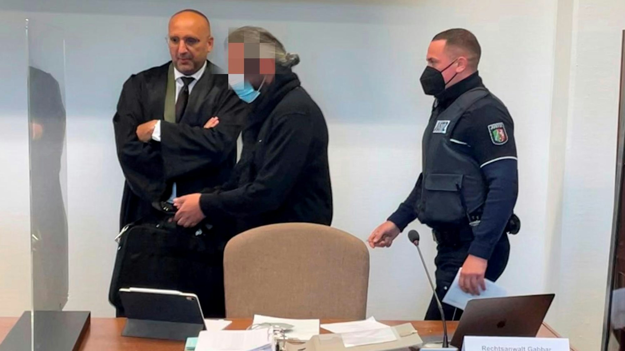 Der Angeklagte mit Verteidiger Abdou Gabbar und einem Wachtmeister im Kölner Landgericht.