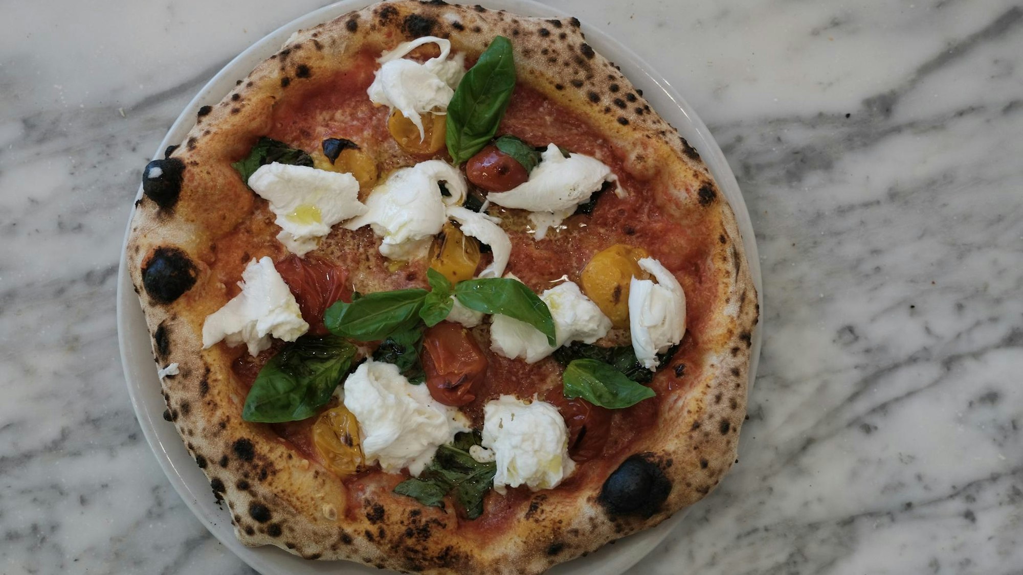 Eine köstlich aussehende Pizza liegt auf einer Marmor-Arbeitsplatte.