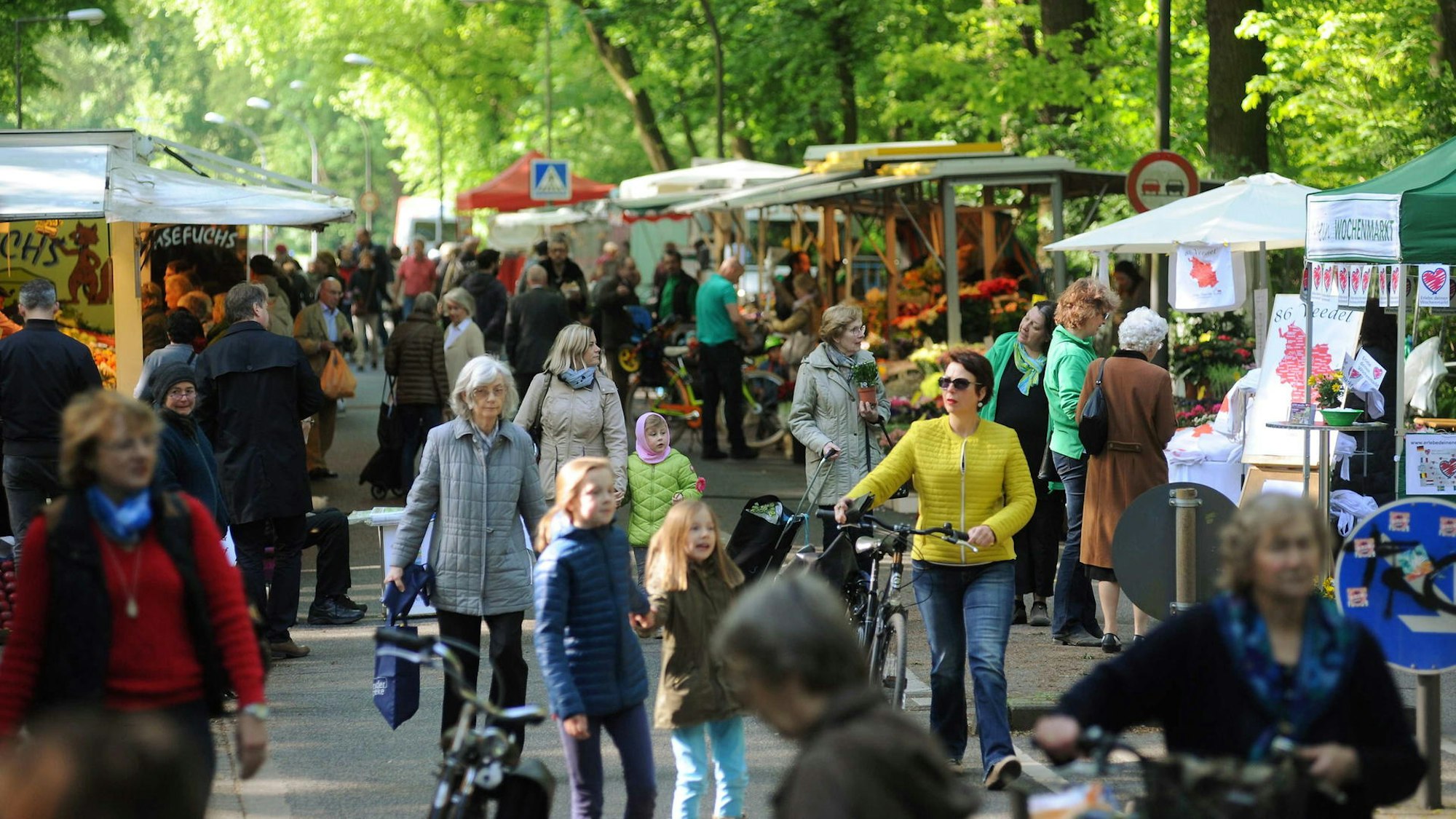Menschen laufen auf einem Weg zwischen Marktständen