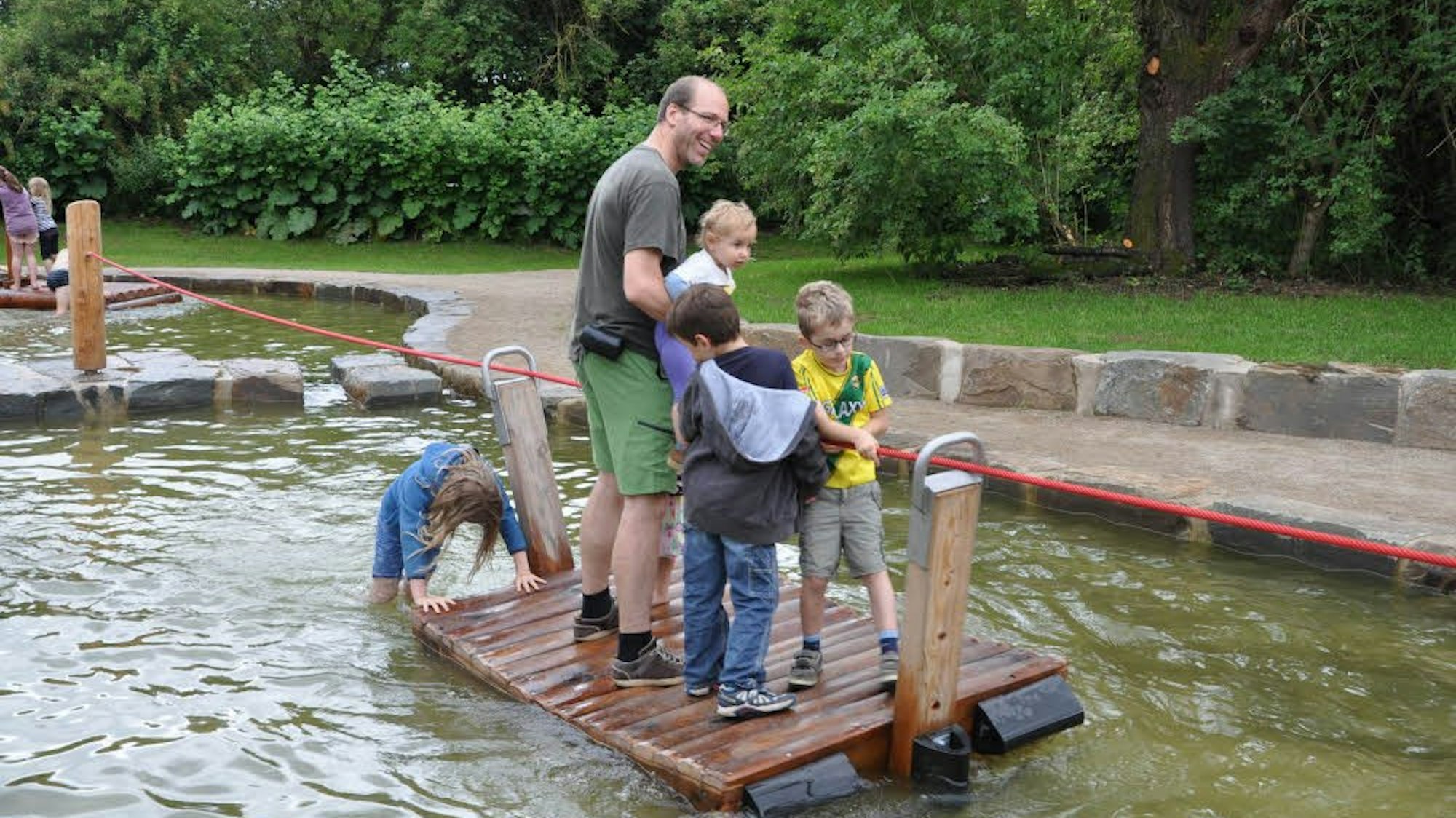 Mann und Kinder stehen auf einem Floß auf dem Wasser