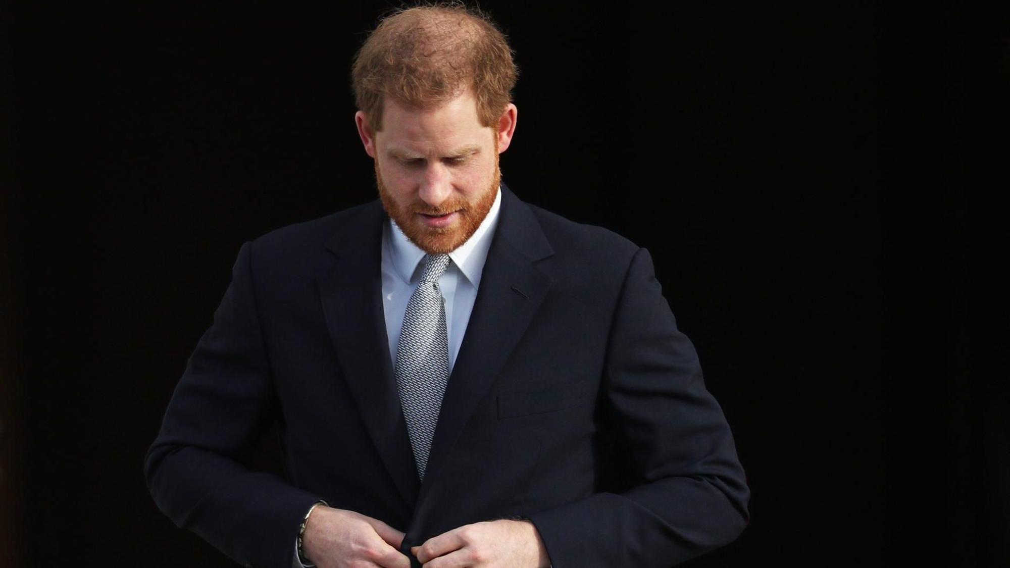 Prinz Harry knöpft sein Jackett zu.
