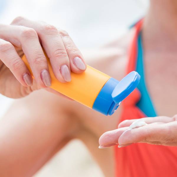 Frau cremt sich mit Sonnencreme ein